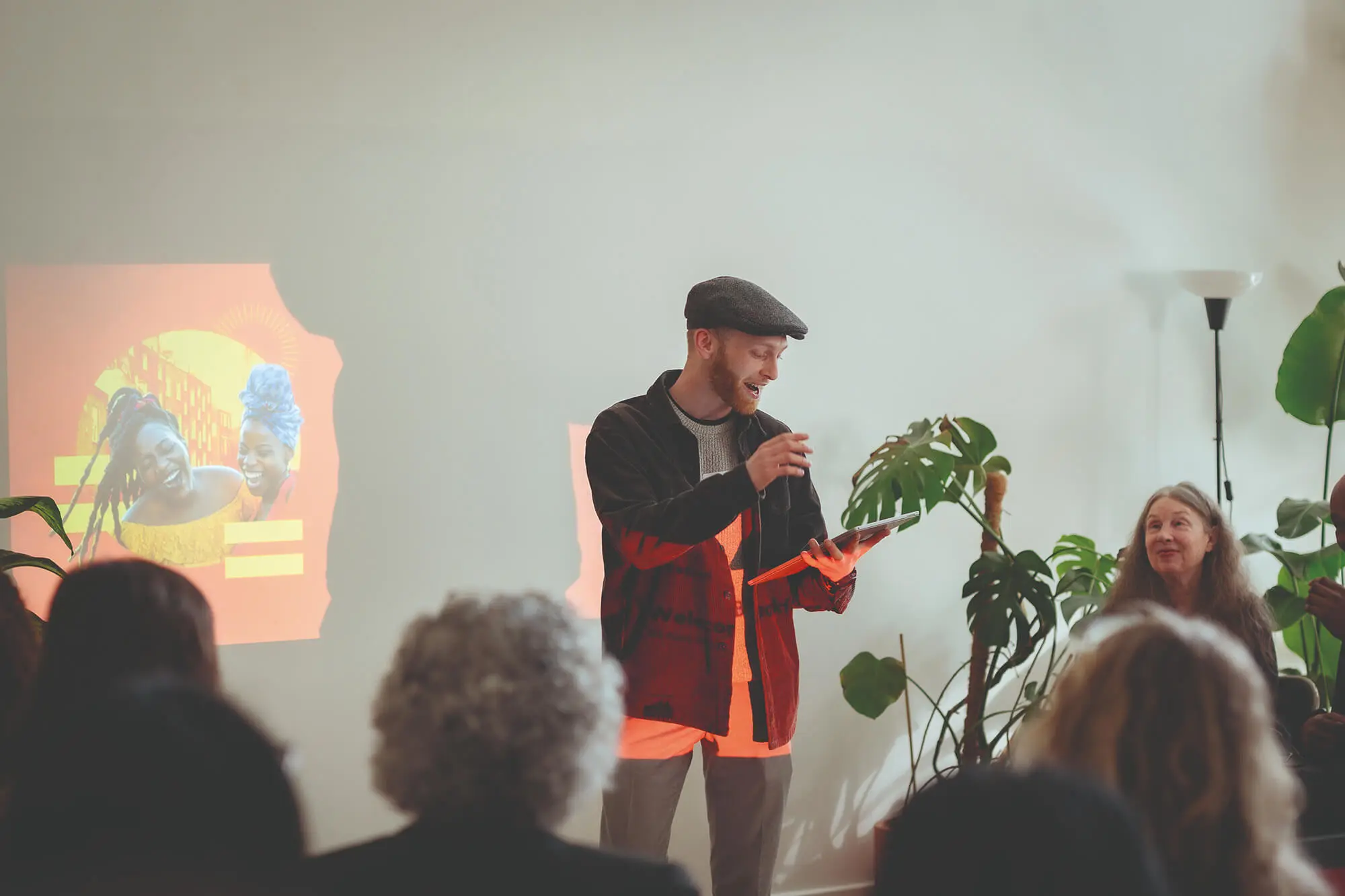 A man holding a tablet talks to seated crowd